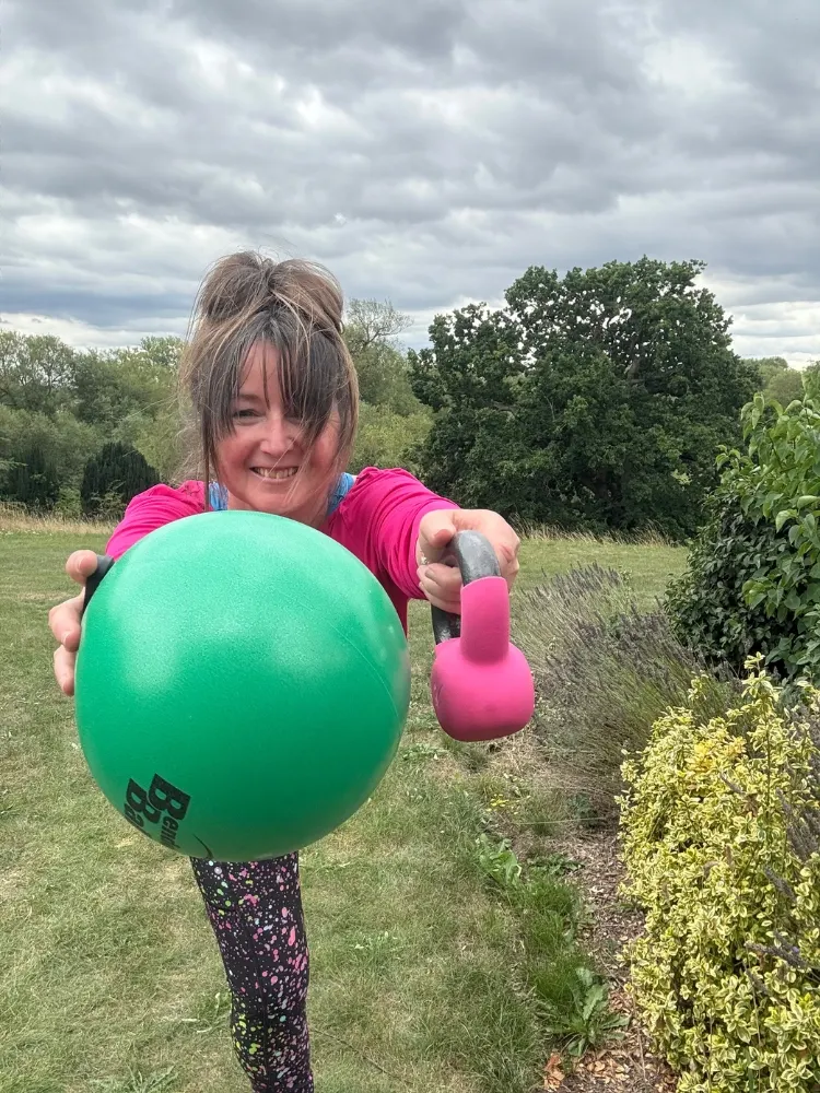 Close-up of instructor holding a kettlebell and stability ball during a functional training session.