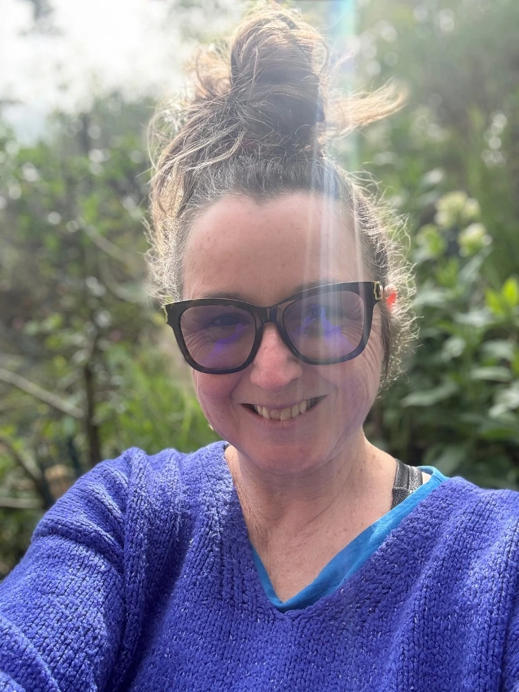 Mairi Taylor smiling outdoors in a garden setting wearing sunglasses.